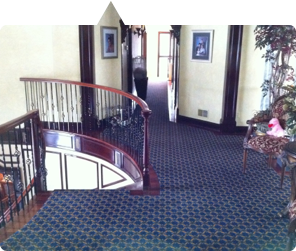 Custom carpet installation featured in NJ magazine — spiral staircase with dark navy patterned carpet